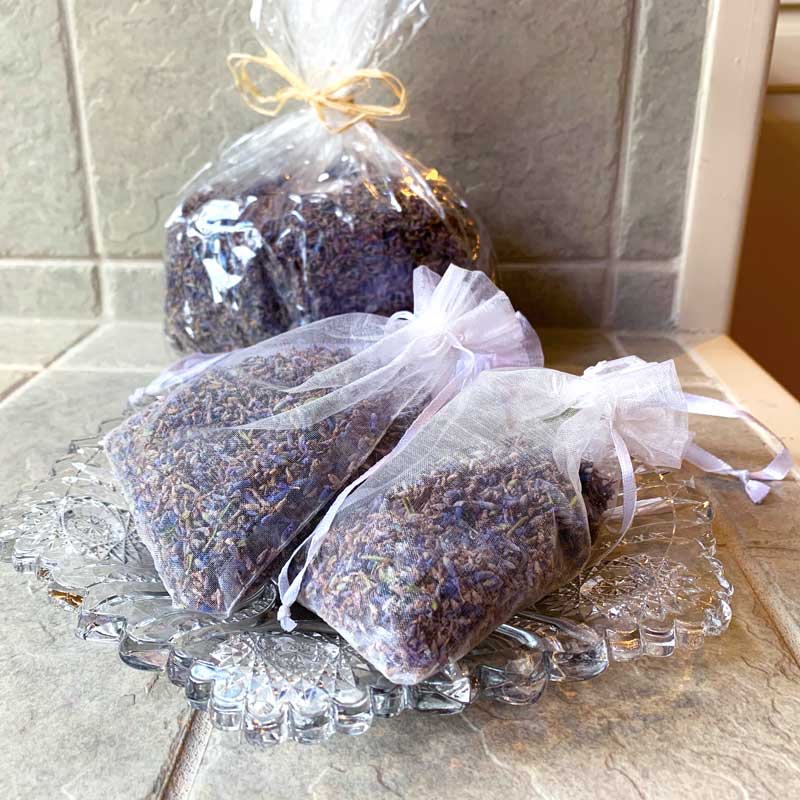 Three perforated bags with dried lavender on crystal dish with four cup lavender bag in background